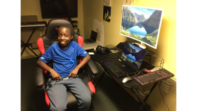 Matthew sits proudly in his new gaming chair in front of his new computer in his bedroom.